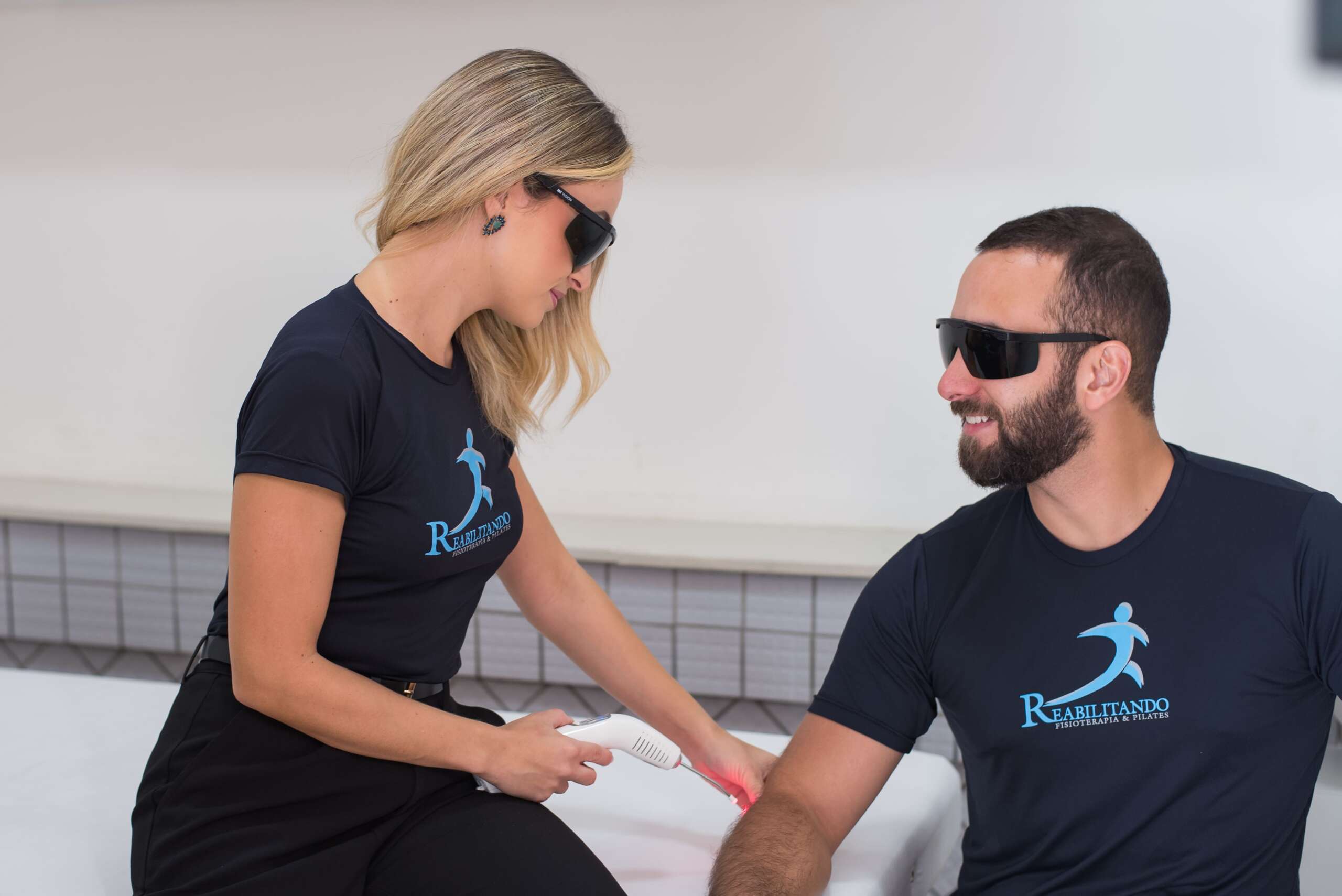 paciente olhando para a fisioterapeuta enquanto tem seu cotovelo cuidado